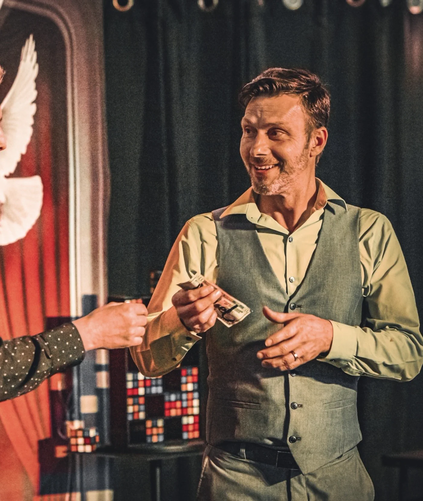 A guest on stage holding a signed bill as doves fly behind him