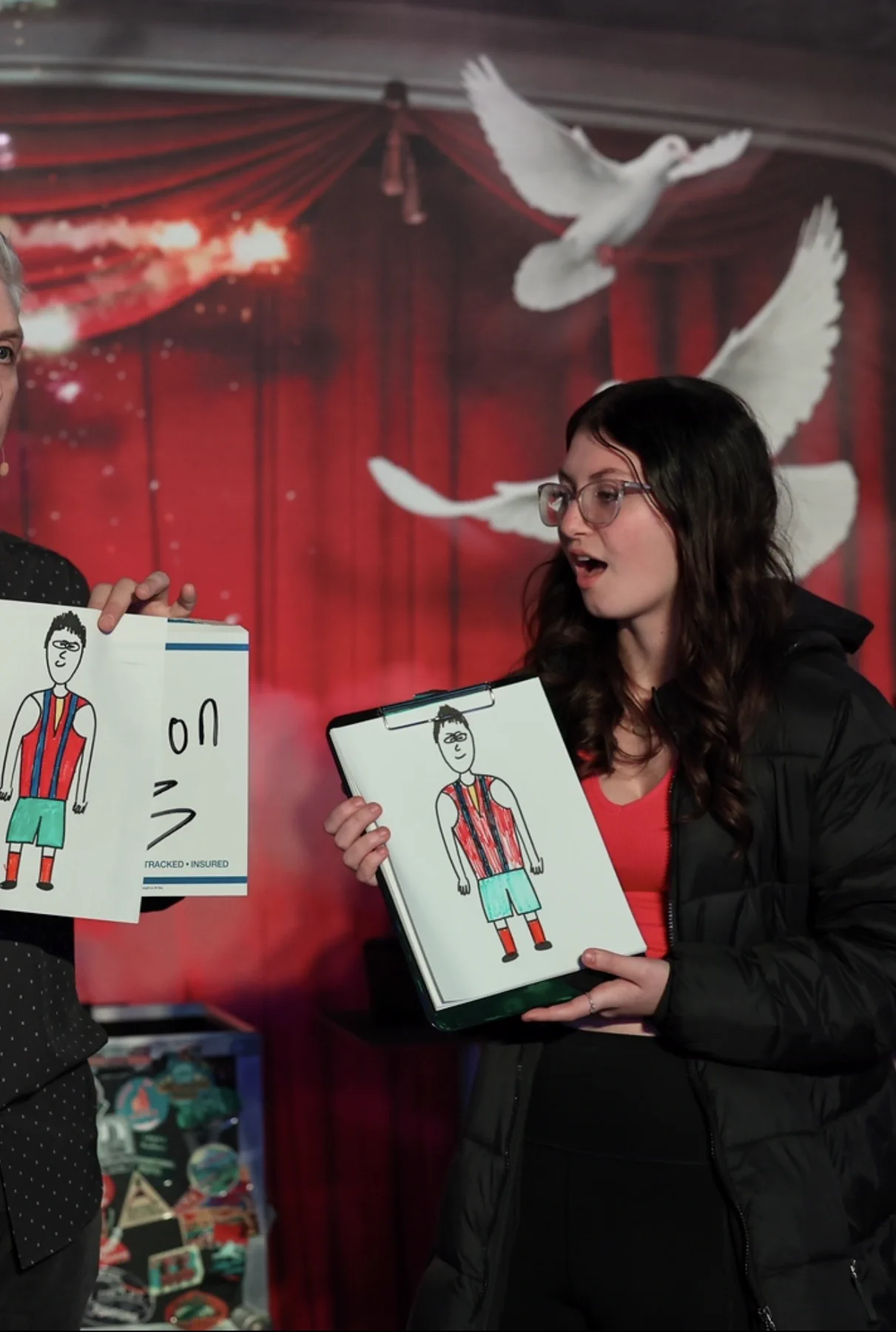 A guest showing her drawing on stage as doves fly behind her