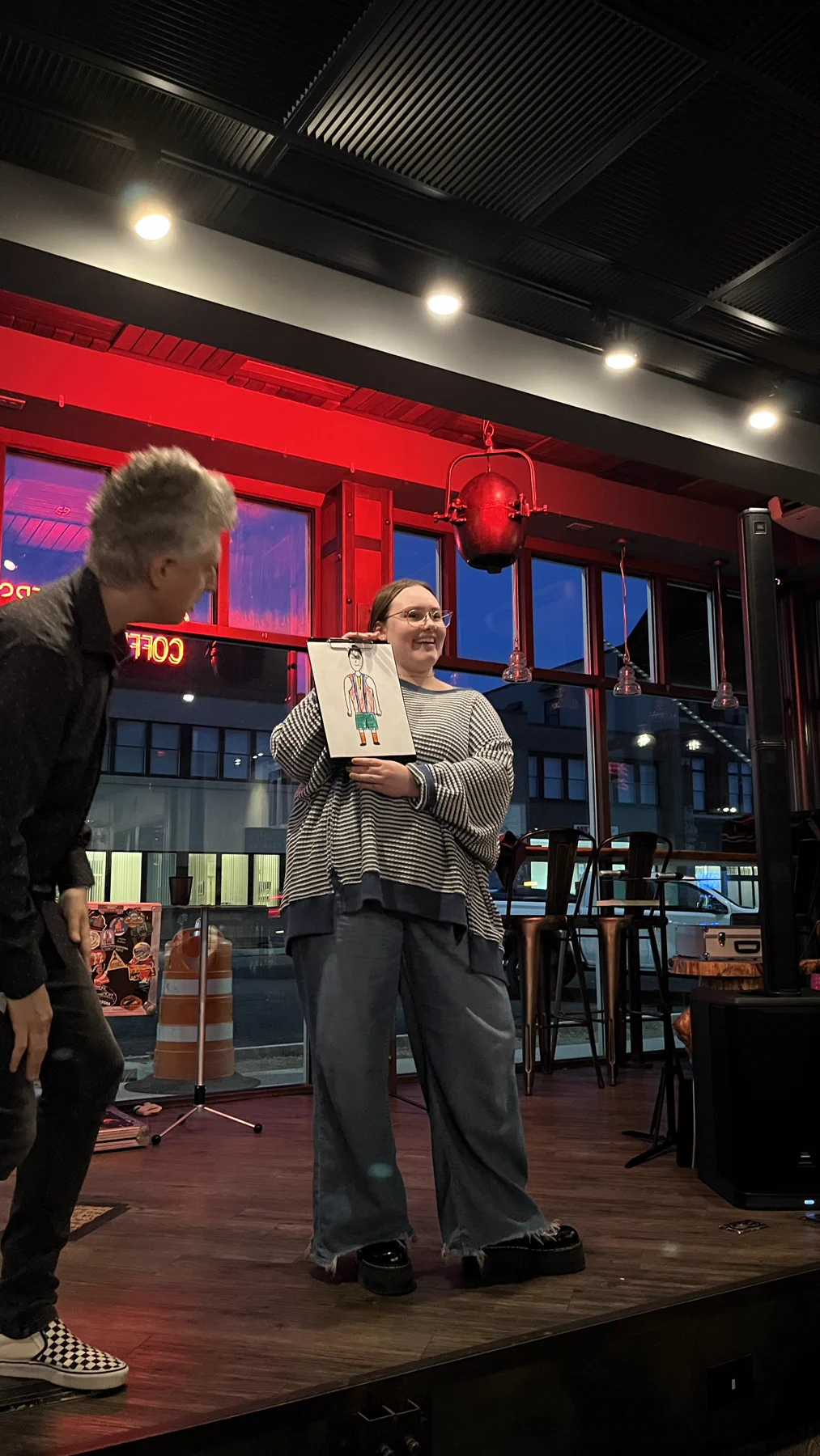 A volunteer holding up her drawing on stage