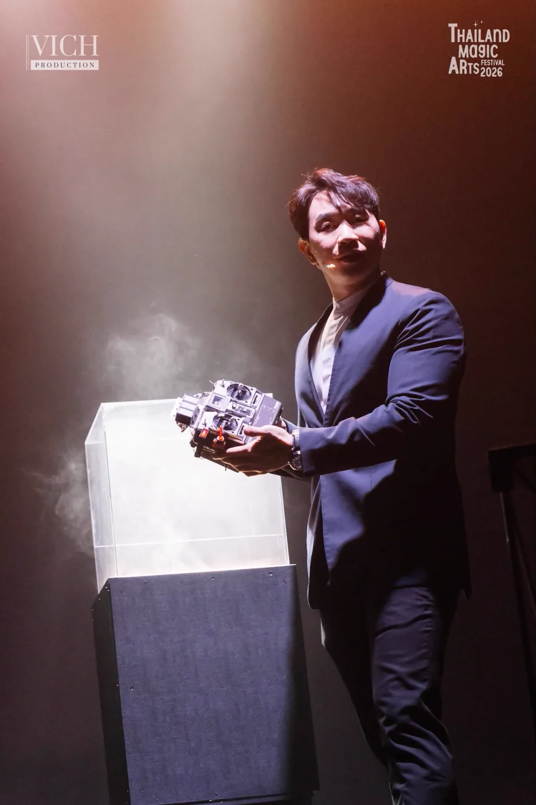 Patrick Kun on stage holding The Remote beside a smoke filled case during Magic Dreams
